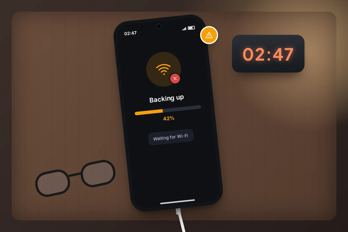 Phone charging on a bedside table at night, showing a backup paused at 42 percent with a Wi-Fi warning