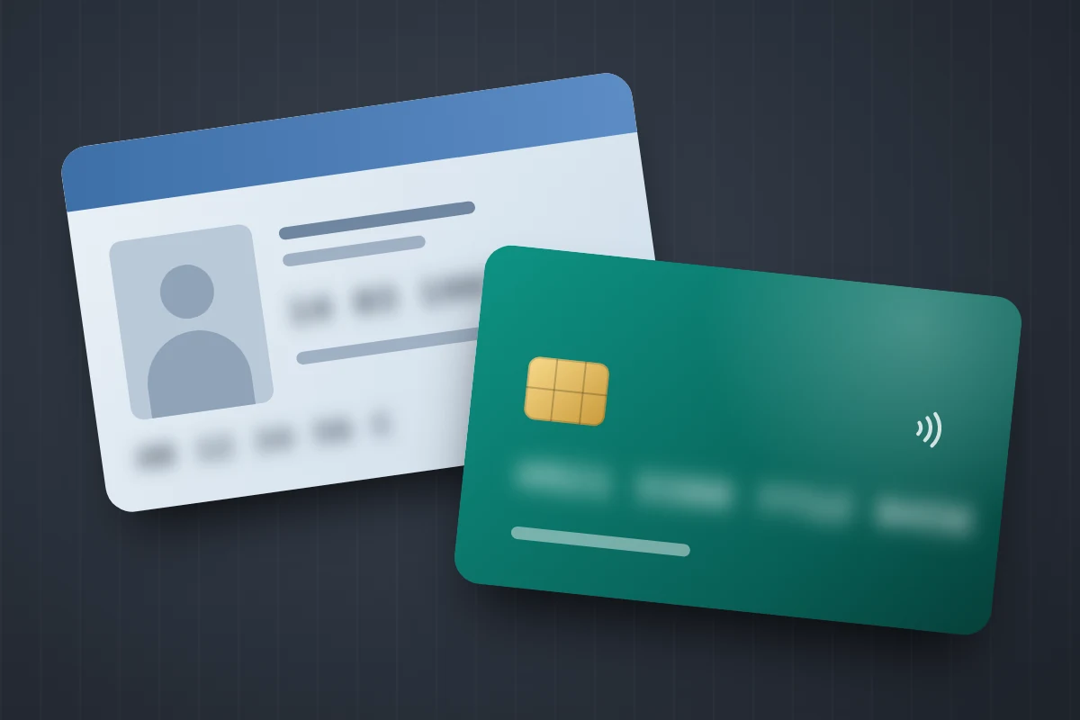 Close-up of an identity card and a bank card on a dark surface with the numbers blurred out