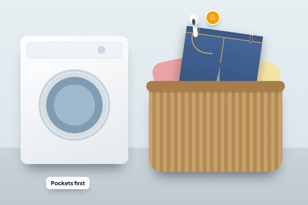 A laundry basket of clothes beside a washing machine, with an earbud visible in the pocket of a pair of jeans
