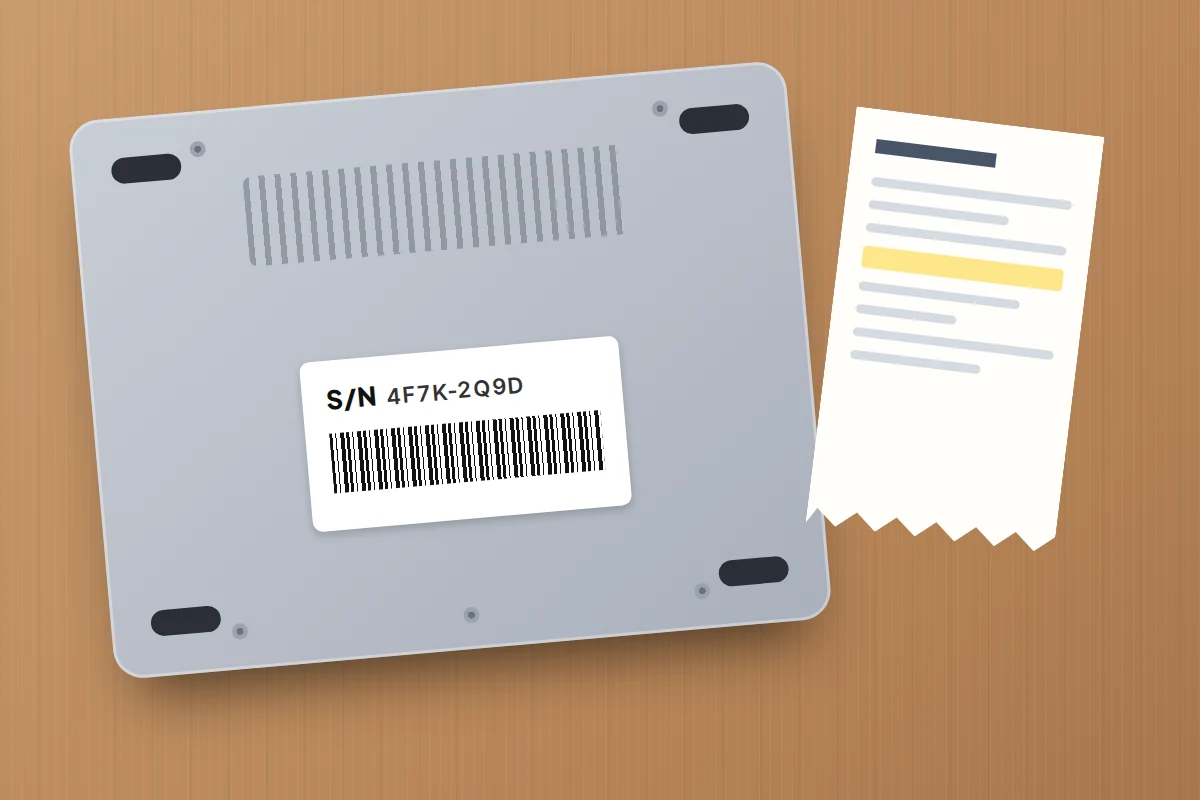 The underside of a laptop with a serial number sticker and barcode, next to a paper receipt on a wooden desk