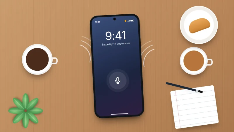 A phone lying on a breakfast table between two cups of coffee, with faint sound waves and a microphone symbol on its screen