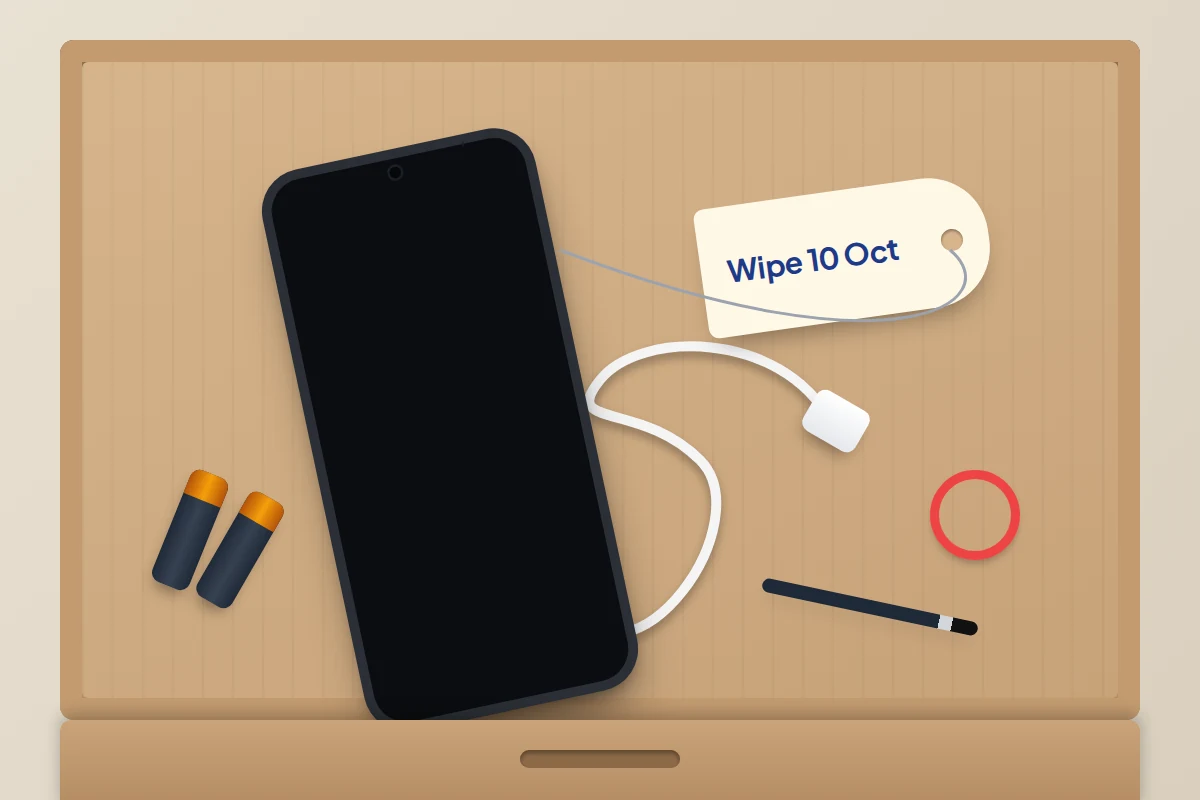 Open drawer seen from above with an old phone, its charger and a paper tag with a date to wipe it