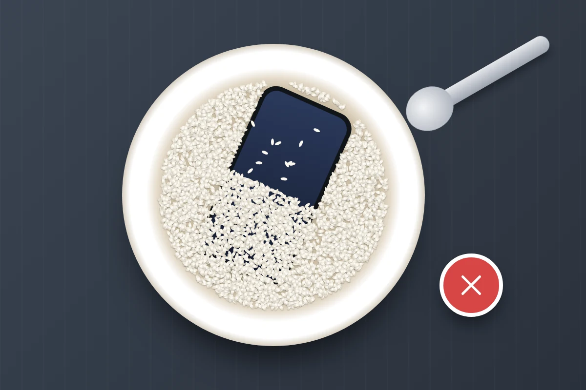 A phone half buried in a bowl of rice with grains scattered on its screen, marked with a red cross