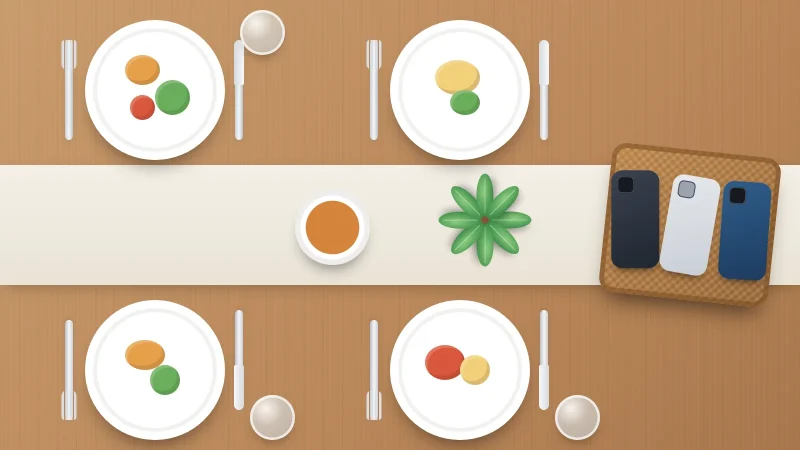 Family dinner table from above with four plates and the phones placed together in a basket at the end of the table