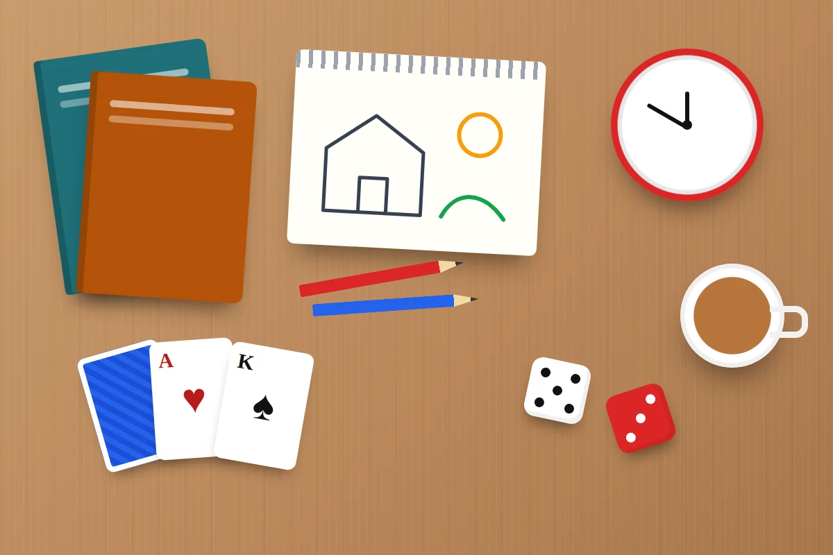 Flat-lay of books, a sketchbook with pencils, playing cards, dice, an analogue alarm clock and a mug of tea