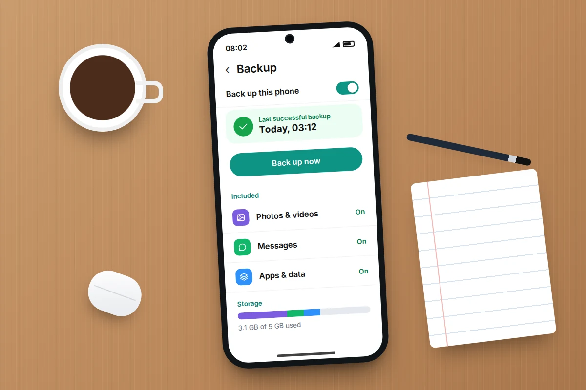 A phone on a wooden desk showing backup settings switched on, with a last successful backup of today at 03:12
