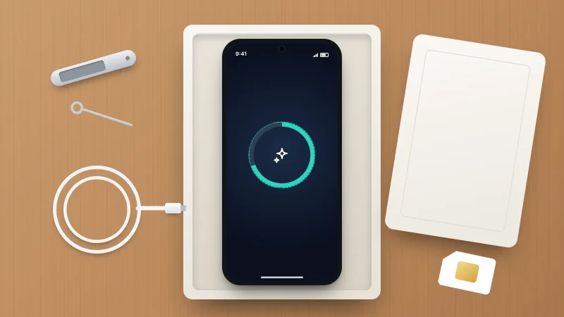 A phone lying in an open box showing an erase progress ring, with a SIM tray, SIM tool, SIM card and charging cable on a wooden table